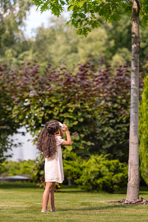 Girl inspecting trees in yard to help see if they need tree service in Atlantic County