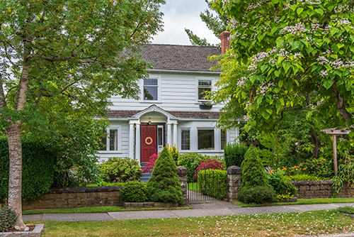 White historic-looking home with a mature landscaped cared for by tree service in Smithville by Ben Bivins Tree Experts